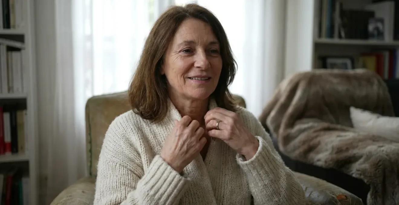 Femme ajustant son pull en maille texturée dans un intérieur chaleureux